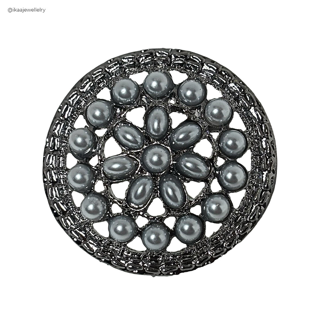 Close-up of a delicate, intricate Paridhi Saree Pin with floral motifs and pearl accents.