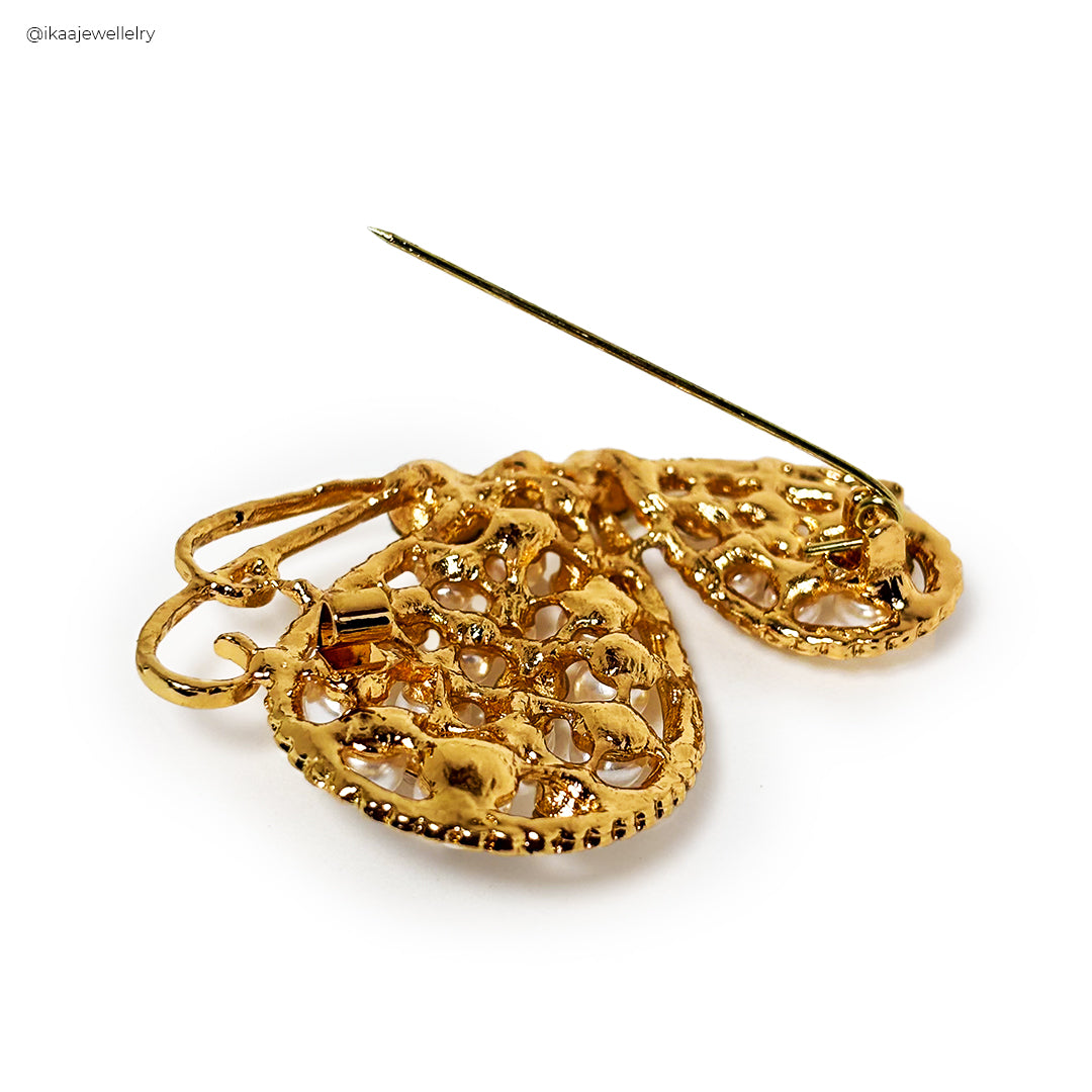 Close-up of a gold Titli Saree Pin with intricate butterfly wing details, designed to secure a saree.