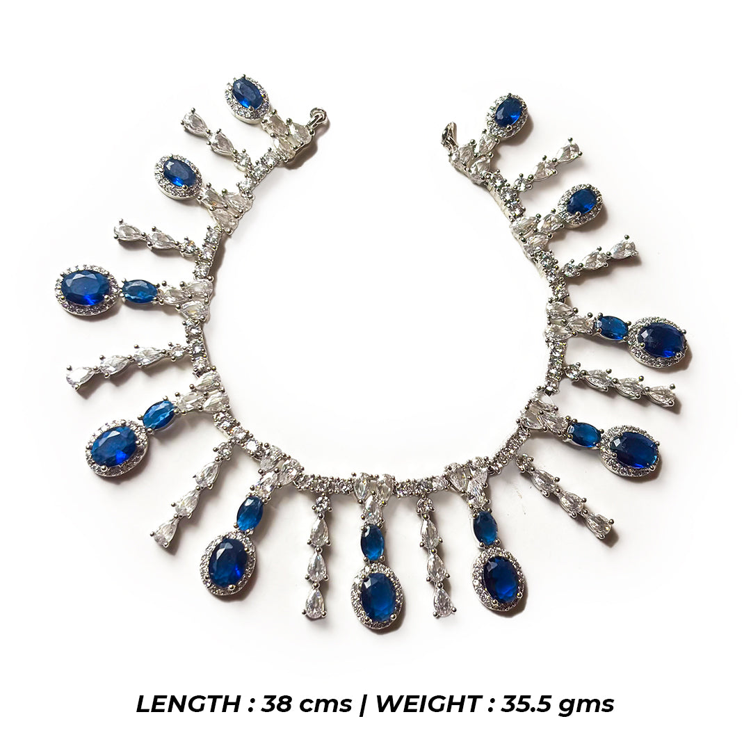 The Indriya Necklace Set features a gold-toned necklace and matching earrings with intricate floral designs and pearl