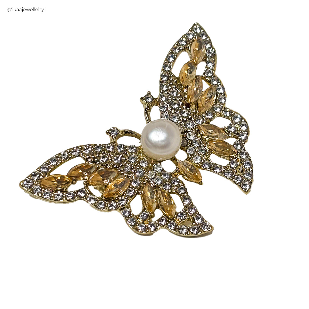 A close-up of a Kanchan Saree Pin / Brooch, featuring intricate gold-toned floral detailing and a central pearl.