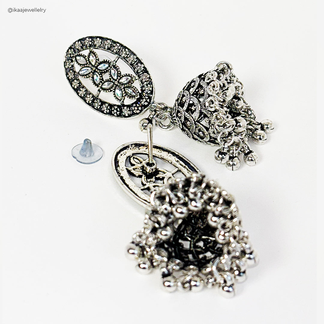 Aruni Jhumki Earrings: Close-up of ornate gold-toned jhumki earrings with intricate carvings and pearl accents.