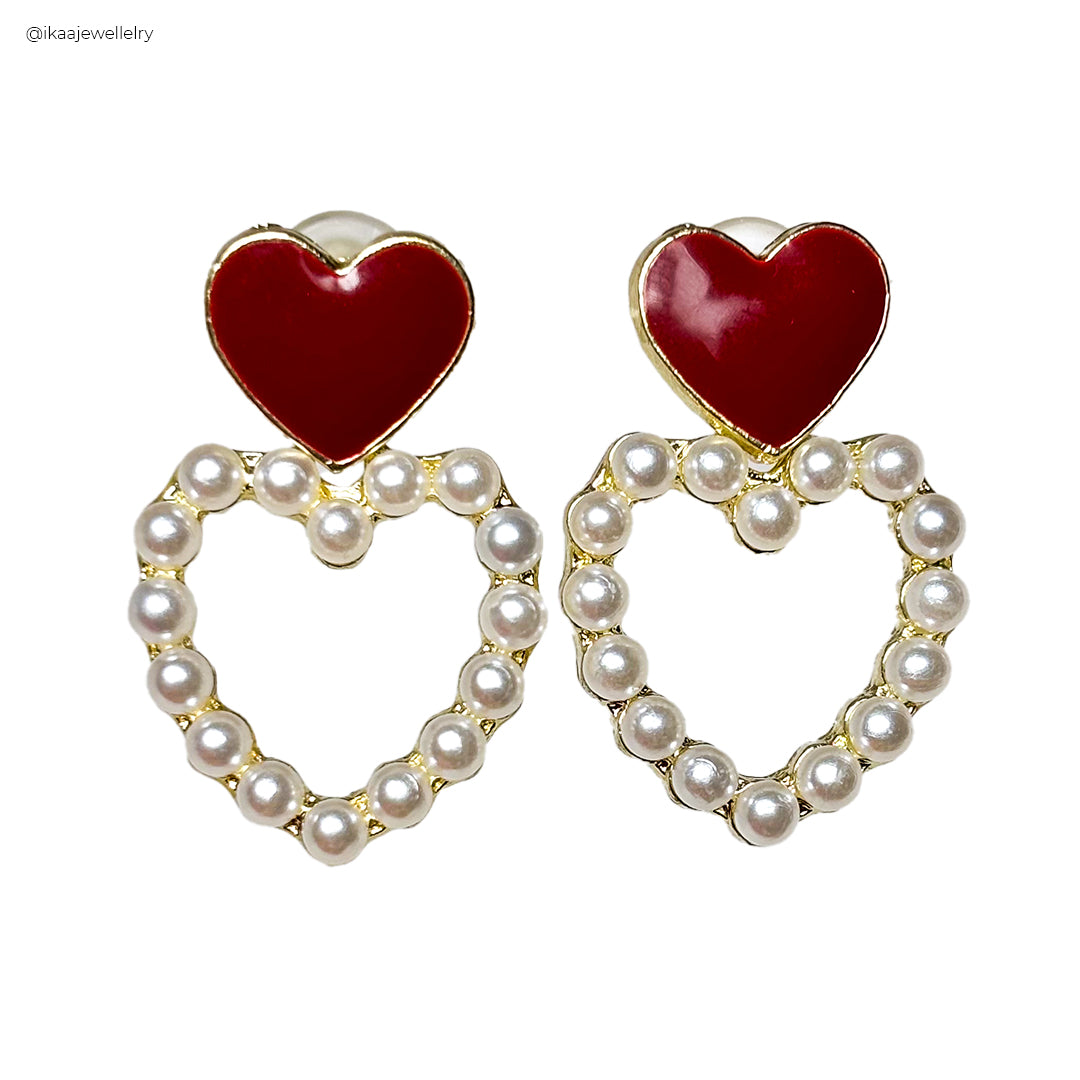 Close-up of Premika Earrings featuring intricate gold-toned filigree work and a dangling pearl accent.