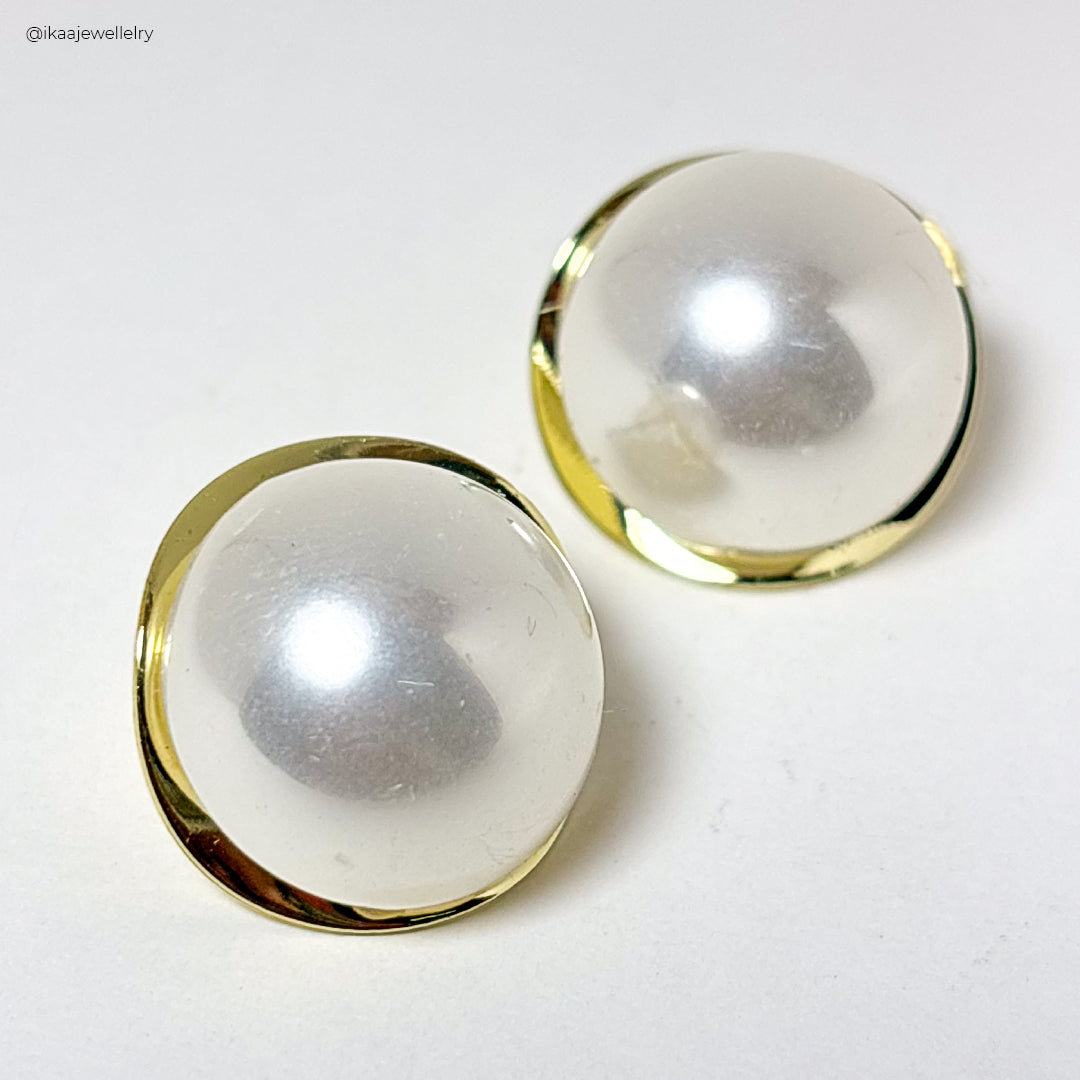 Close-up of Ruva Earrings: delicate gold hoops with a single pearl drop, showcasing elegant simplicity.