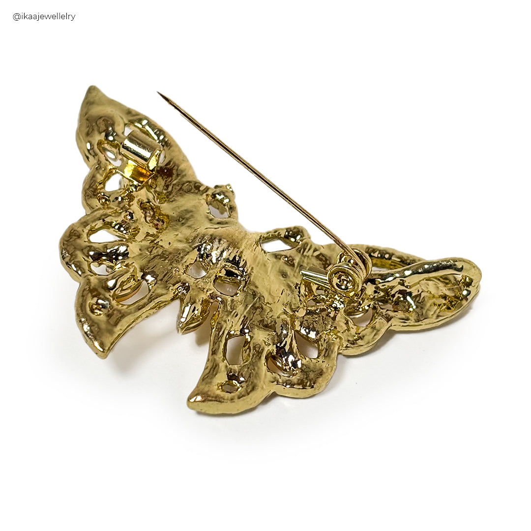Close-up of a Kanchan Saree Pin / Brooch, featuring intricate gold metalwork and a central ruby-red stone.