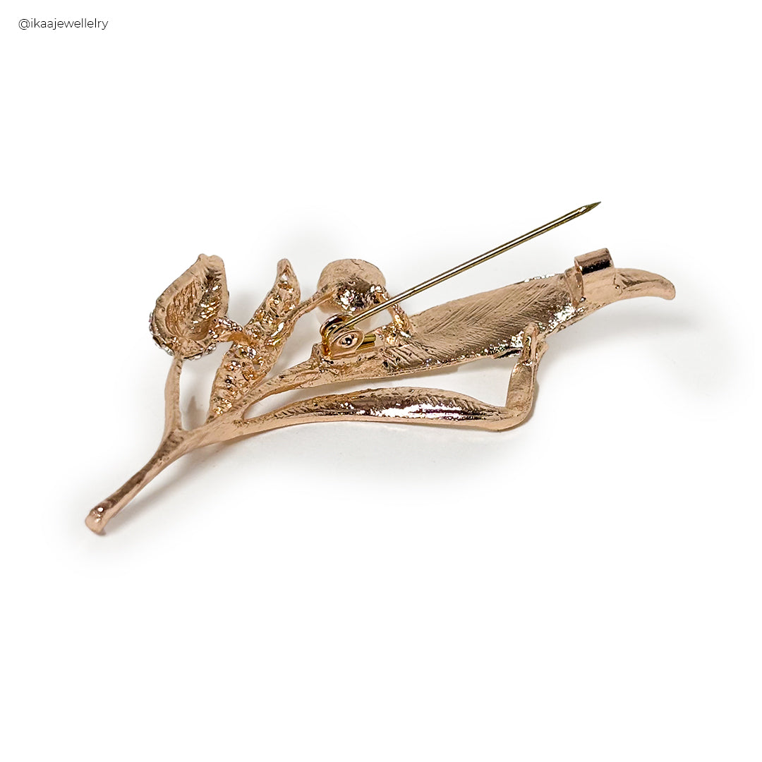 A Ziya Saree Pin with intricate floral metalwork and a prominent pearl accent.