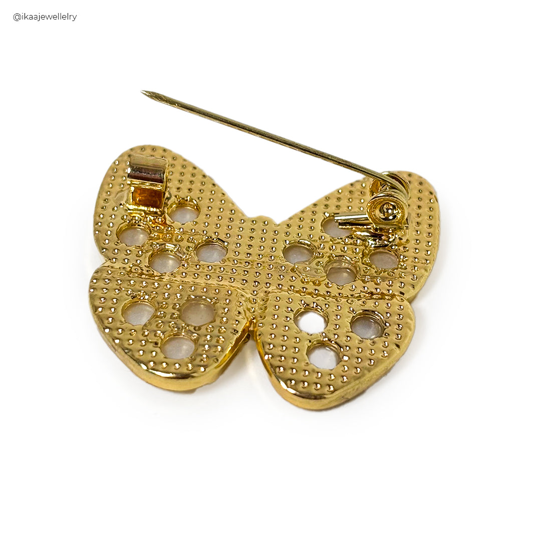 Close-up of an elegant Urvi Saree Pin featuring intricate golden meenakari floral design with red and green accents.