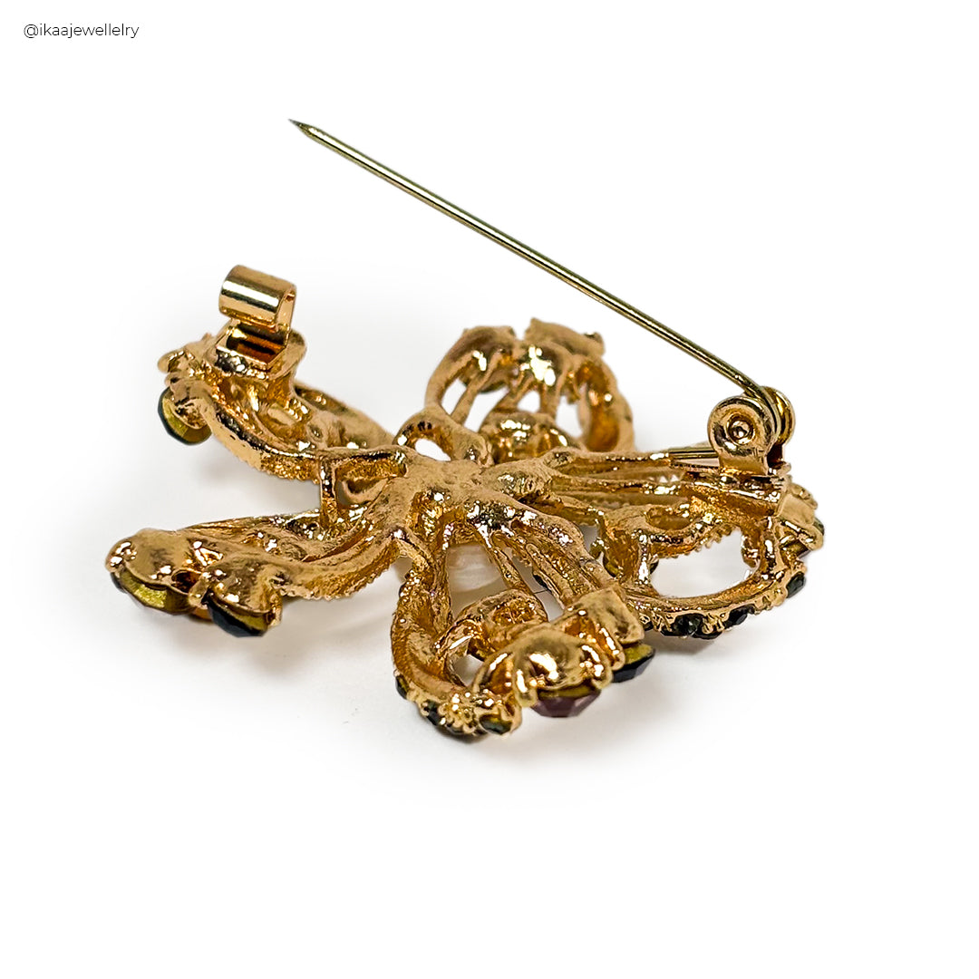 Mahika Saree Pin: A close-up of a gold-toned saree pin shaped like a delicate flower with pearl accents.