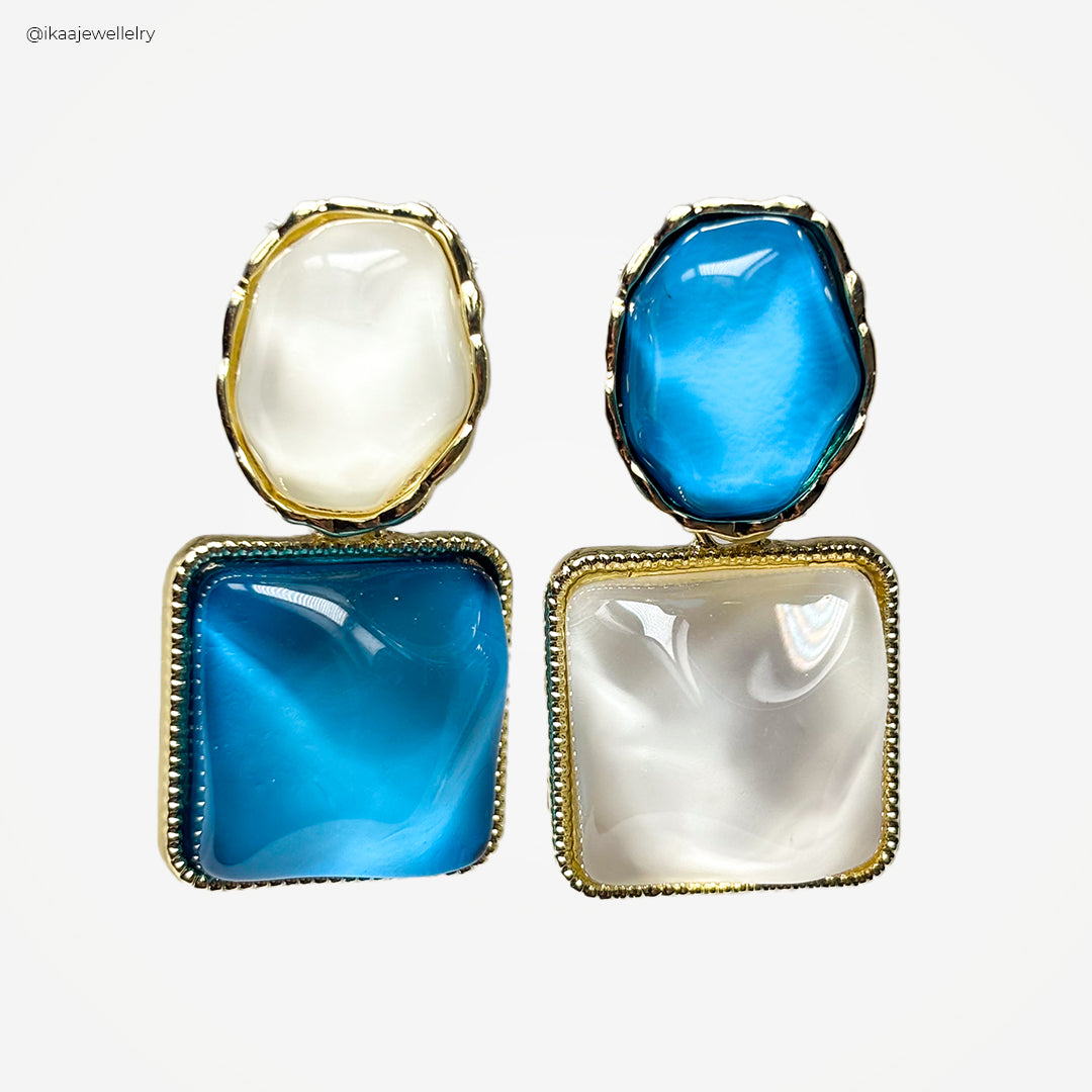Close-up of the Mira Earrings: delicate gold hoops with a subtle hammered texture and a small, shimmering pearl drop.