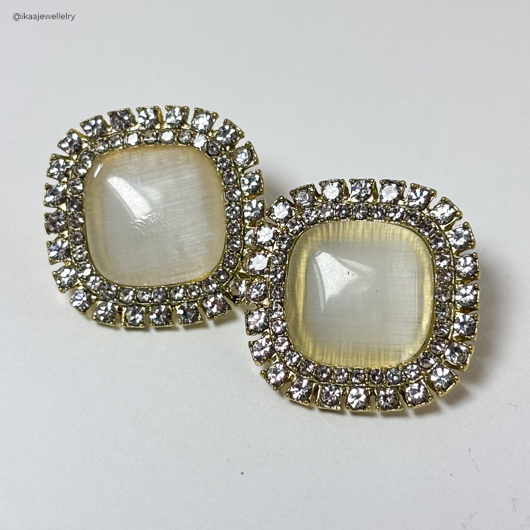 Delicate gold Niva Earrings with intricate floral detailing, showcased on a soft, grey background.