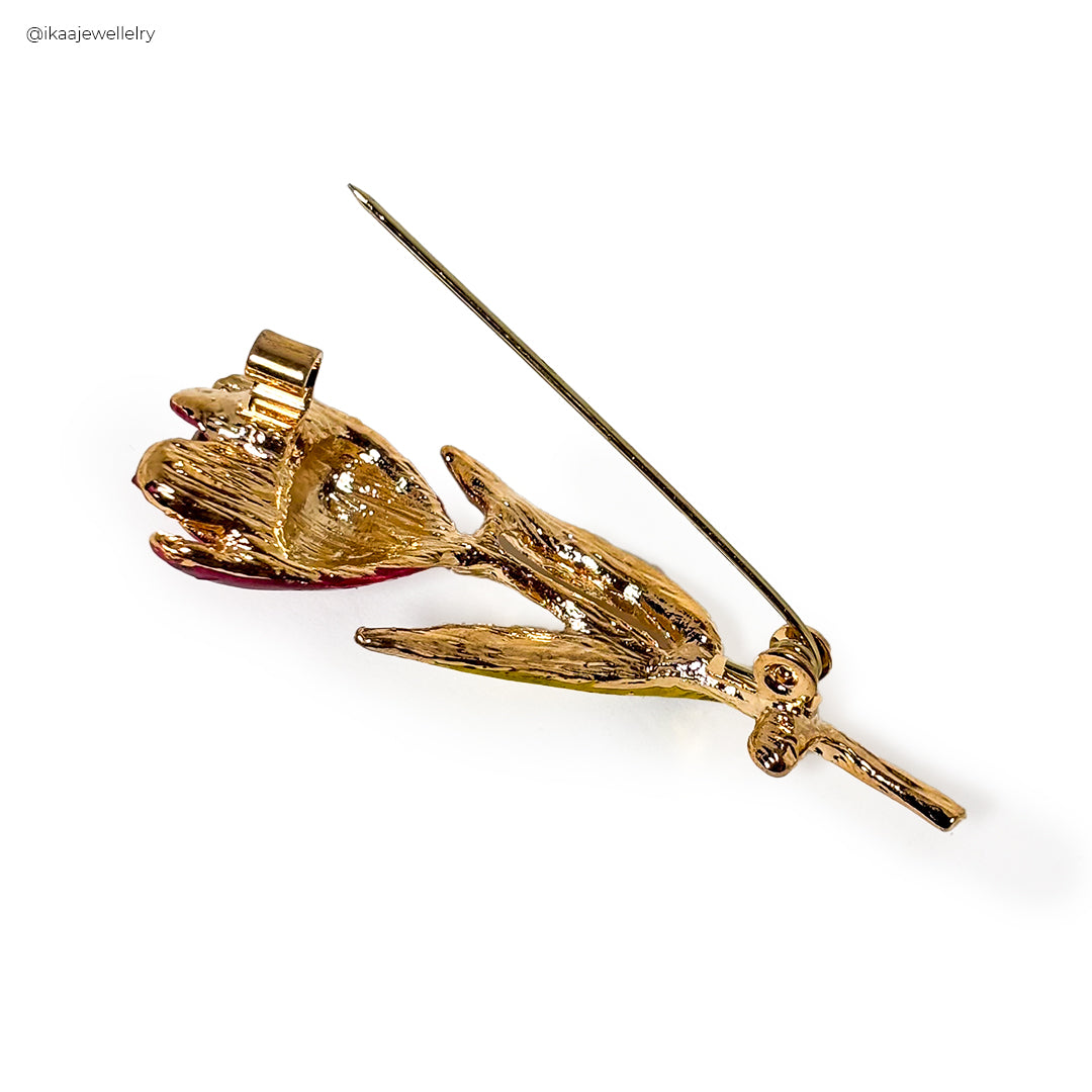 Arunika Saree Pin: A close-up of a gold-toned saree pin with a floral design and small pearl accents.