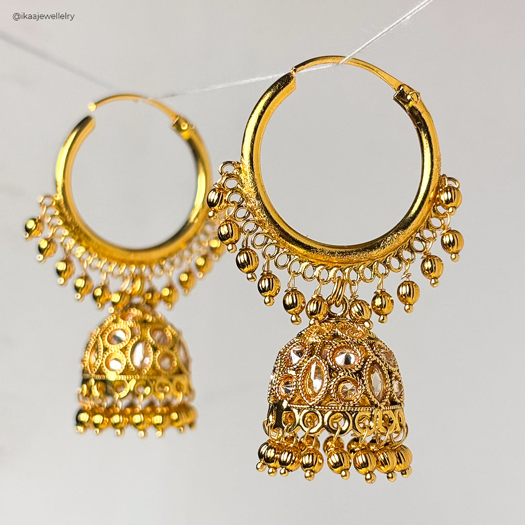 Close-up of Sukanya Earrings: delicate gold hoops with intricate floral detailing and small pearl drops.