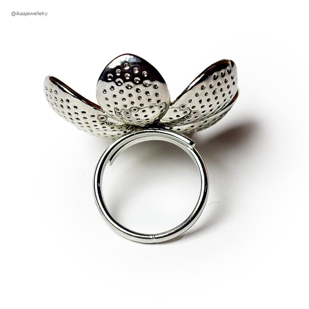 The Arzoo Ring, a delicate gold band with a central blue sapphire, rests on a white surface.
