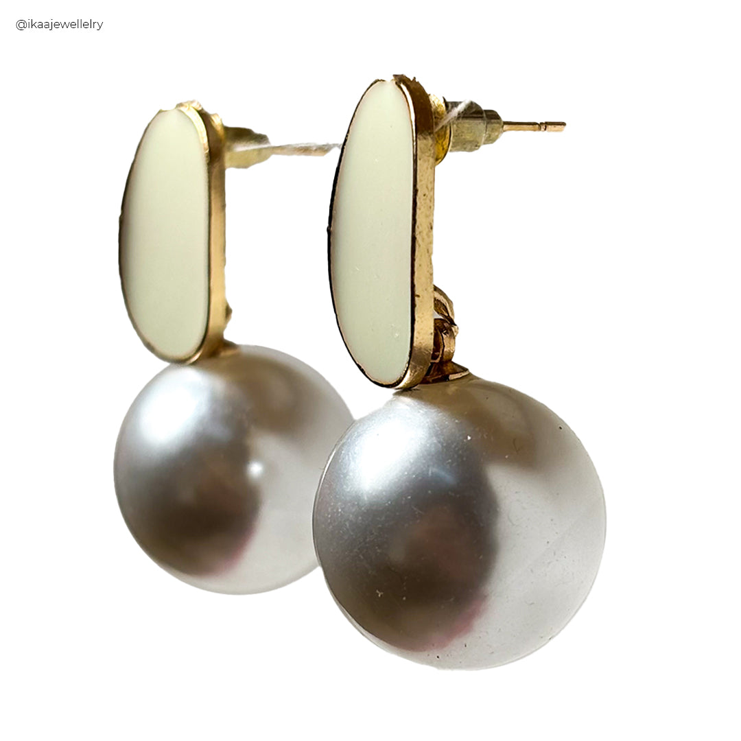 Close-up of delicate Mila Earrings with small pearl drops and gold hoops.
