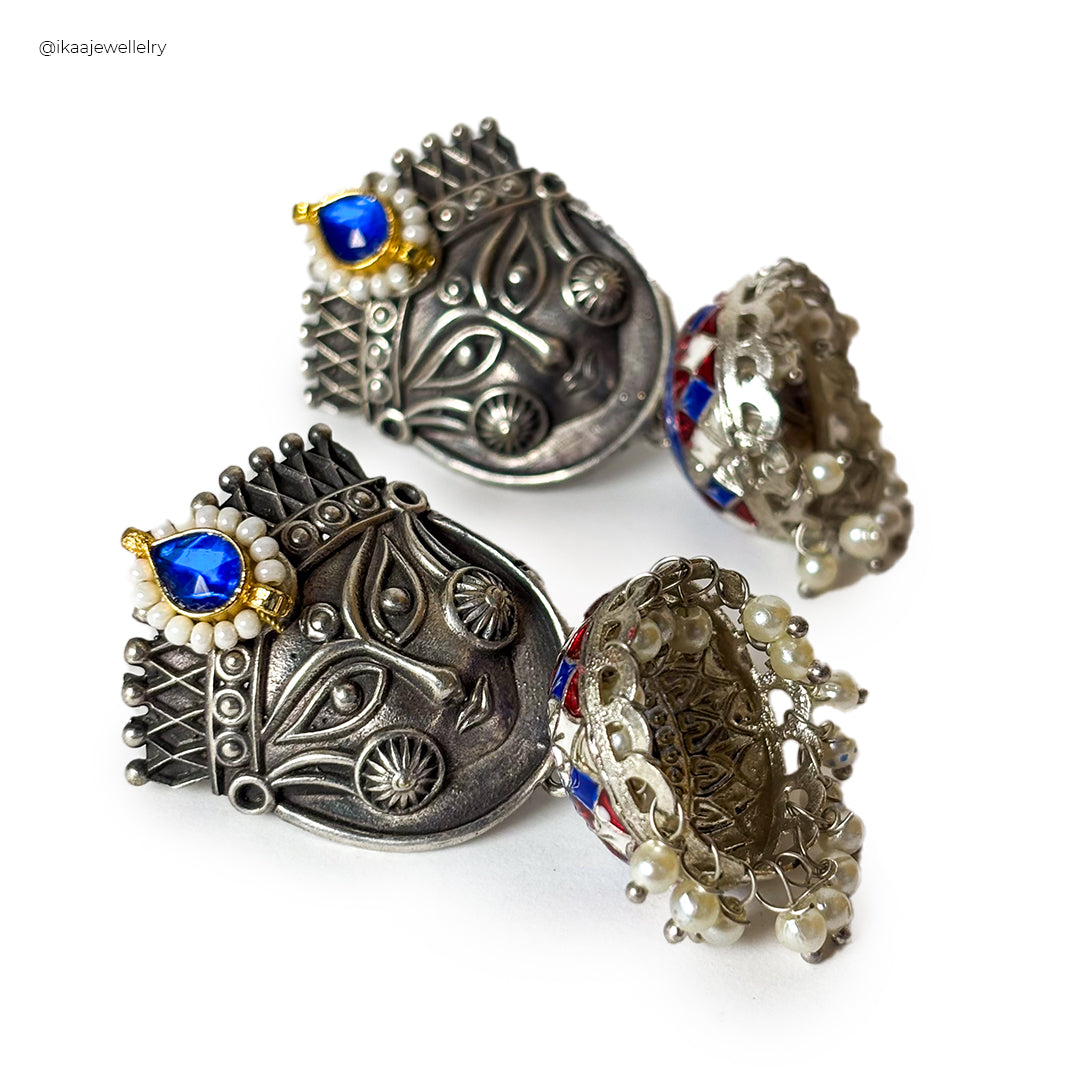 Close-up of Trinetri earrings featuring intricate gold wirework in a circular design with small pearl accents.