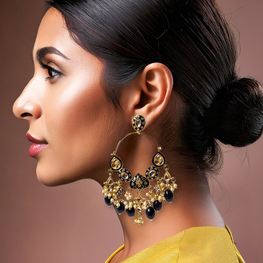 Meghini Chandbali Earrings: intricately designed gold-toned chandbali earrings with pearl drops and red stone accents.