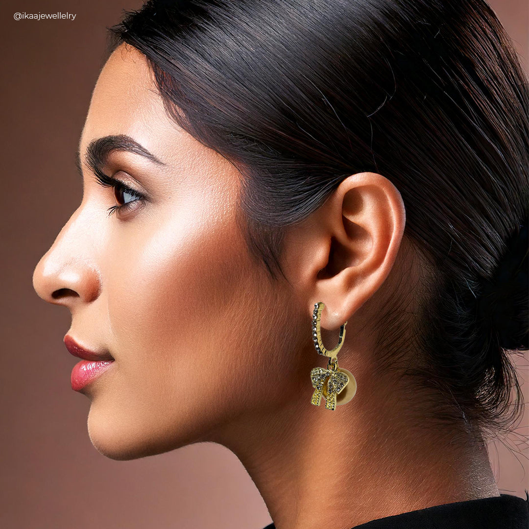 Close-up of Orna Earrings: intricate gold floral design with delicate pearl drops, set against a soft grey background.