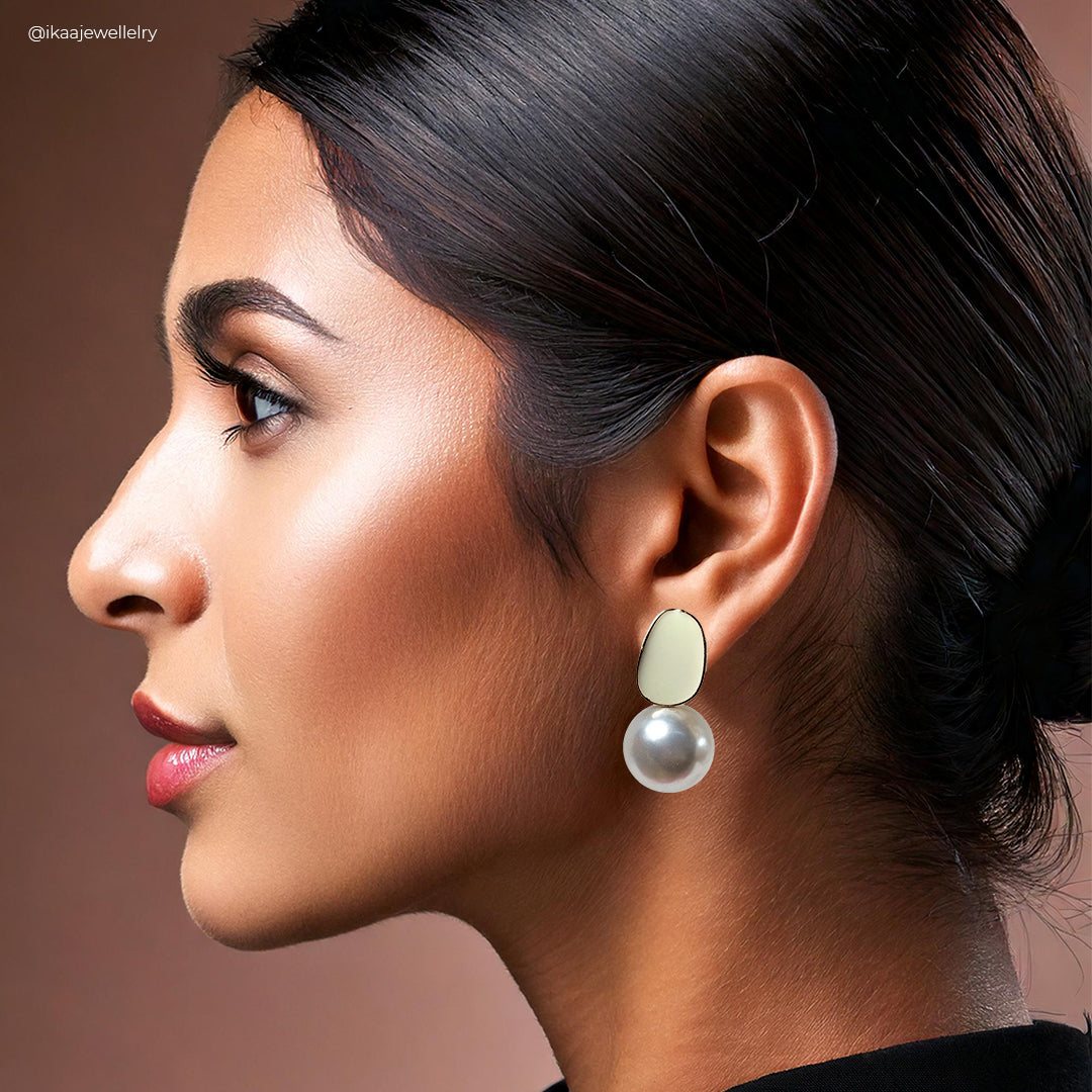 Mila Earrings: Close-up of delicate gold hoop earrings with a small, sparkling gemstone at the bottom.