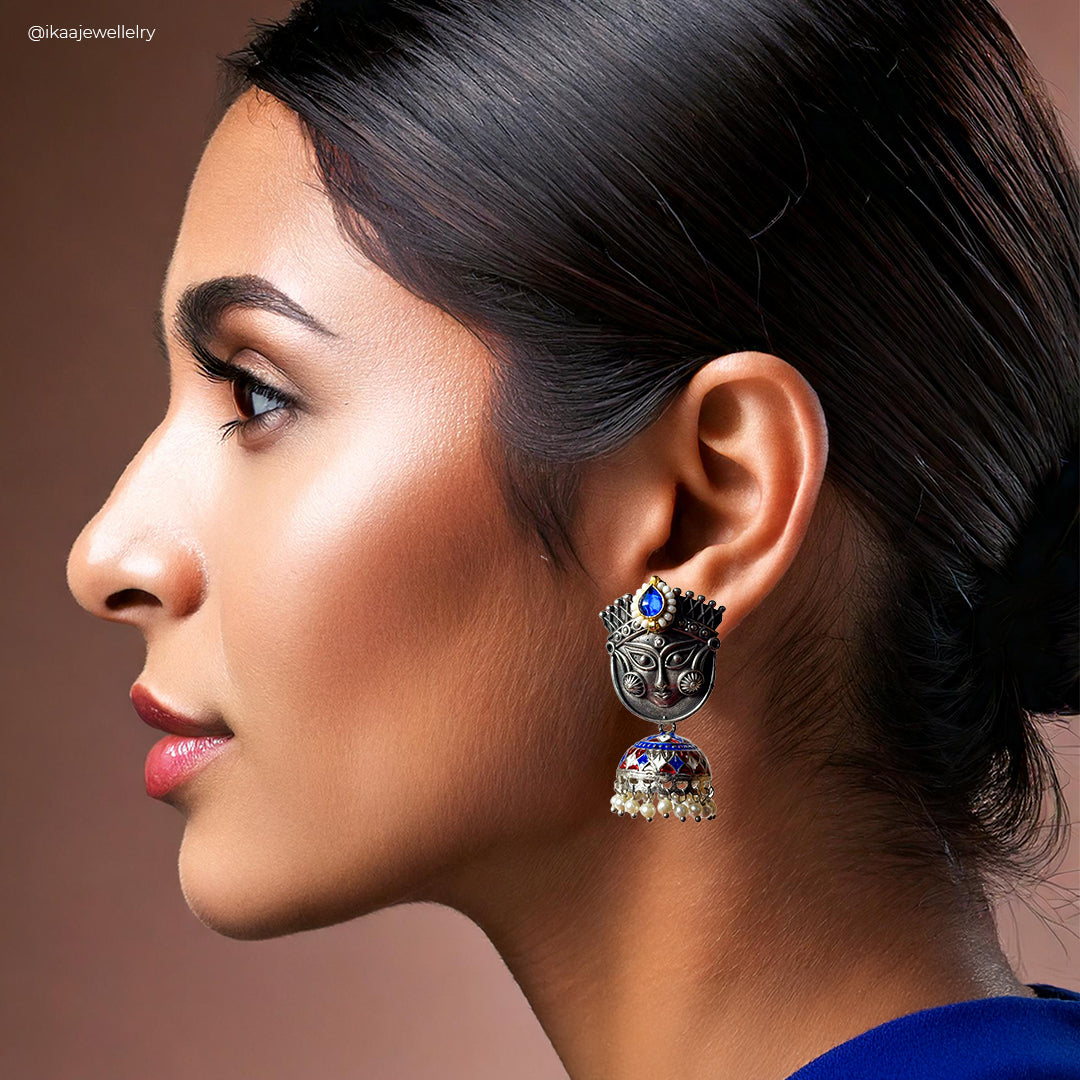 Close-up of elegant Trinetri Earrings with intricate gold metalwork and small pearl accents.