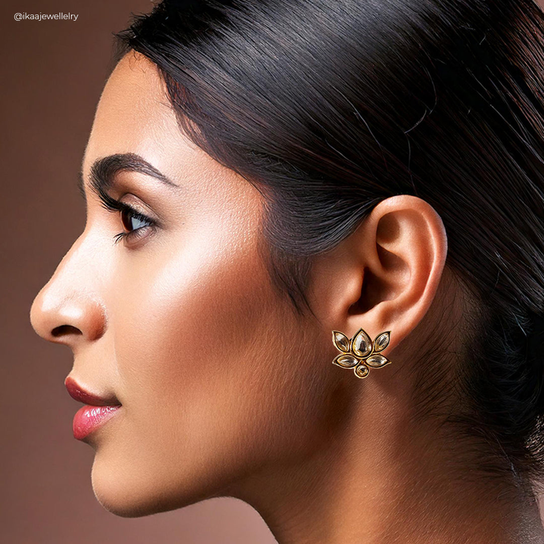 Close-up of the Padma Earrings: delicate gold lotus flower studs with a sparkling gemstone center.