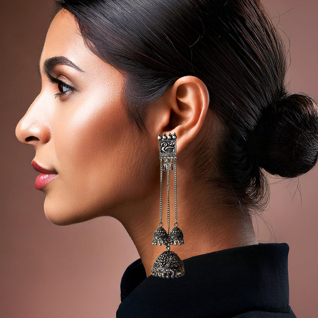 Chitra Long Earrings: a pair of gold-toned, intricately carved drop earrings with a central floral motif.