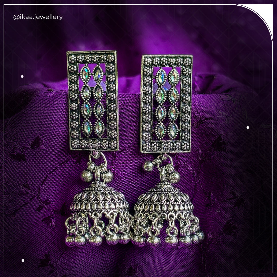 Aruna Jhumki Earrings, a pair of intricately designed gold-toned jhumkas with pearl accents and delicate dangling chains.