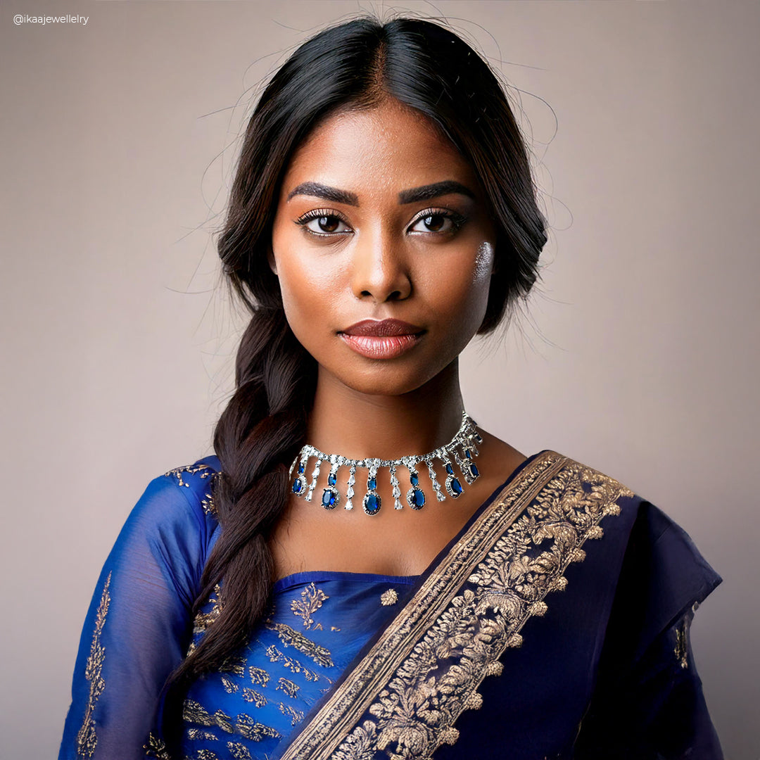 The Indriya Necklace Set features intricate gold-toned metalwork with a central green stone pendant and matching earrings.
